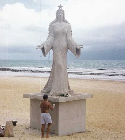 Iemanja on a Brazilian beach. The man is performing a New Year's tribute to the Sea Goddess. (Photo courtesy of Link)