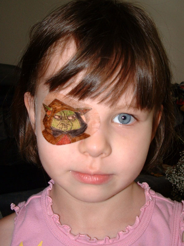 A photograph of a child wearing an eyepatch featuring artwork of the Star Wars character Yoda.